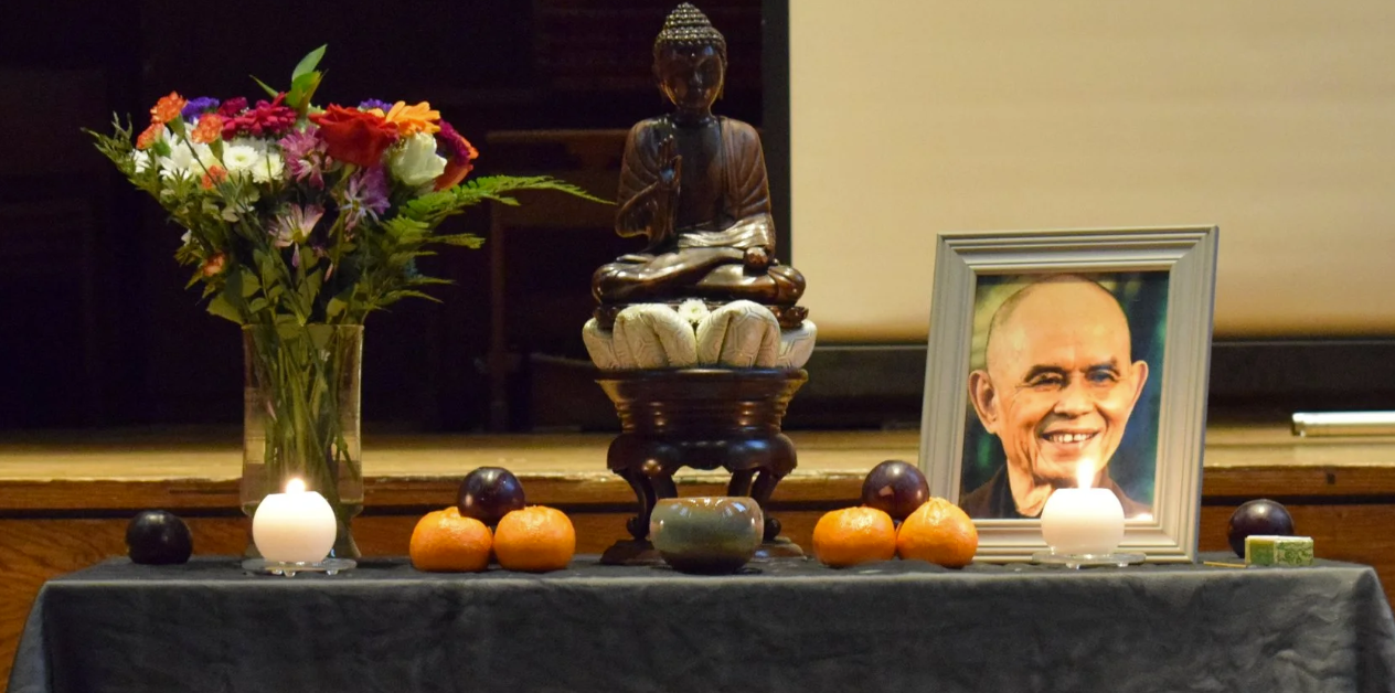 Altar with a Buddha statue, flowers, candles and a portrait of Thích Nhất Hạnh