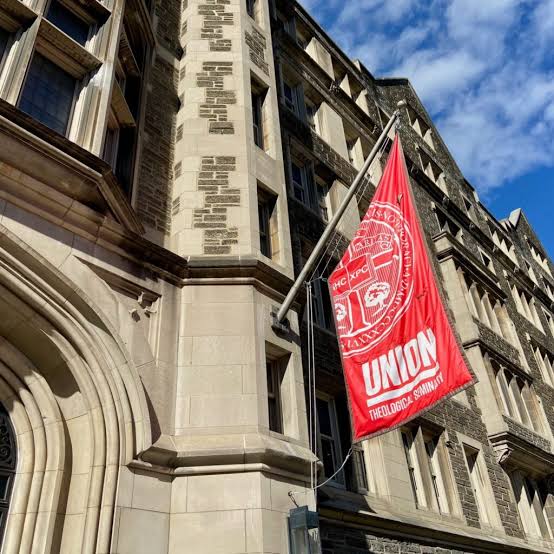 The red Union Theological Seminary flag flying from the stone facade of the seminary building